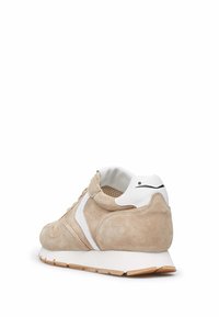 Beige Wildlederschuhe mit weißen Akzenten, gepolstertem Kragen, Mesh-Futter und einer strukturierten Gummisohle. Klassisches Design eines Laufschuhs.
