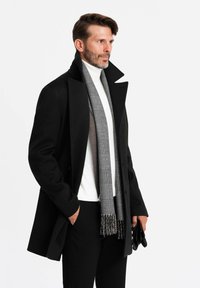 Abrigo negro con cuello alto, suéter blanco de cuello alto, bufanda de cuadros gris y guantes negros. Diseño simple, a medida, con una silueta elegante.