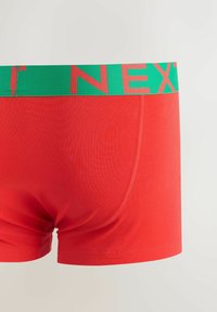Red men's boxer briefs with a green waistband featuring partial bold red text on a plain white background.