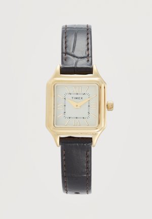 Čtvercové náramkové hodinky Timex se zlatým tónem, bílým ciferníkem, římskými číslicemi a tmavě hnědým koženým páskem s viditelným šitím.