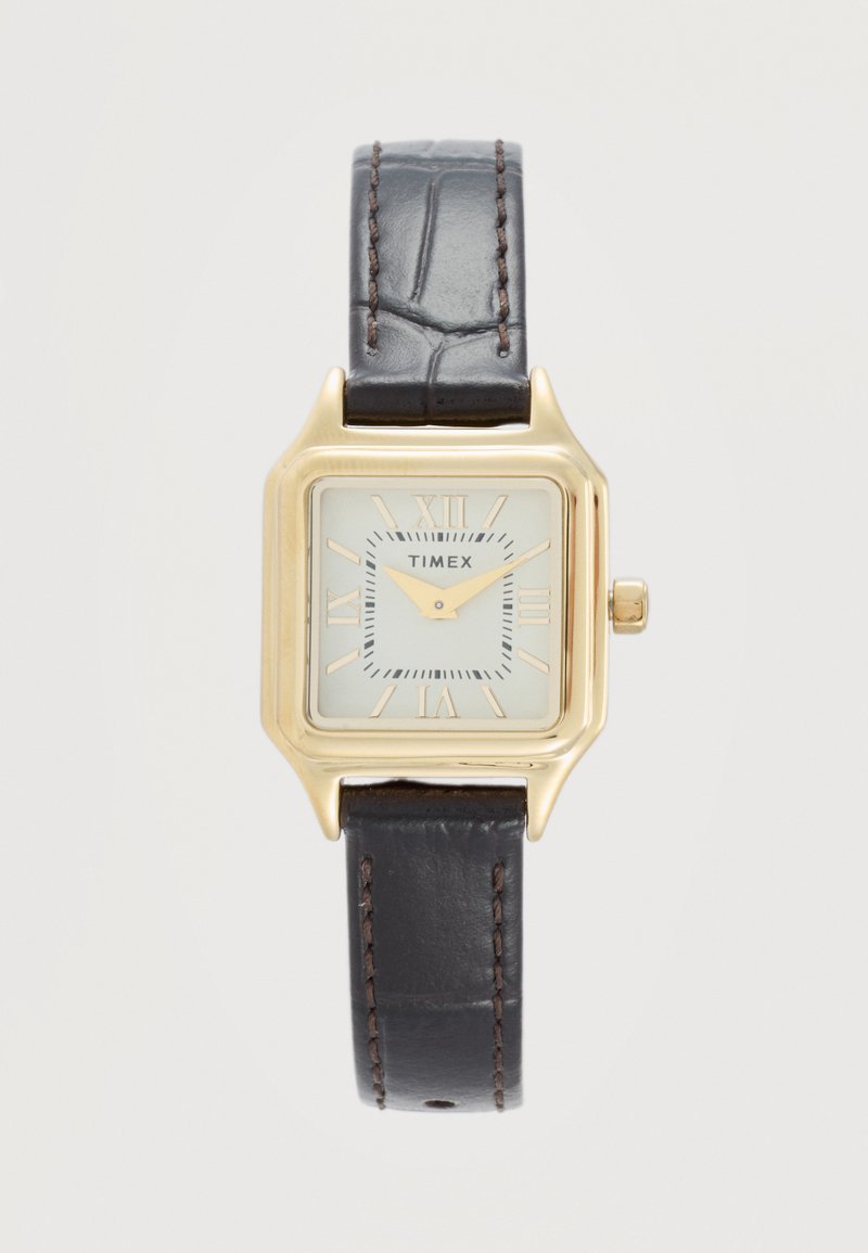 Štvorcové hodinky Timex v zlatej farbe s bielym ciferníkom, rímskymi číslicami a tmavo hnedým koženým remienkom s viditeľným prešitím.