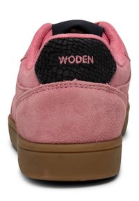 Sneaker in suede rosa con un pannello posteriore testurizzato nero, caratterizzata dal branding "WOODEN" in cuciture rosa sul retro e una suola in gomma marrone.