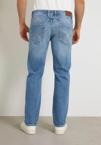 Jeans de mezclilla azul claro con corte de pierna recta. Cuentan con dos bolsillos traseros, una etiqueta de cuero marrón de la marca y detalles sutiles de costura.