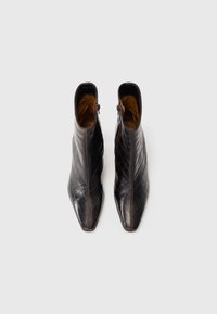 Svarta läderankleboots med ett quiltat mönster, spetsig tå och sidogångjärn. Insidan har en tan-färgad foder.