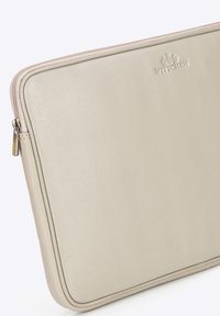 Sleeve per laptop in pelle beige con una finitura testurizzata sottile, dotata di chiusura con zip e logo impresso al centro in alto.