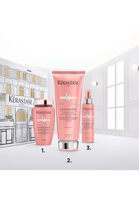 Le set de soins capillaires Kérastase comprend trois tubes roses : un shampooing, une crème de conditionnement avec un capuchon argenté et un sérum sans rinçage, tous étiquetés de manière distincte.