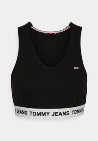Top corto nero realizzato in tessuto liscio. Presenta una profonda scollatura a V e un elastico bianco con la scritta "TOMMY JEANS" stampata in nero.