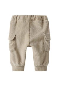 Pantalons en velours côtelé beige avec une taille élastique, deux poches cargo latérales et des chevilles à revers. Le tissu présente une texture côtelée subtile.