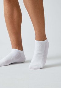 Weiße Knöchelsocken aus Baumwollmischung, mit gerippten Bündchen und atmungsaktiven Mesh-Einsätzen an den Seiten. Fein strukturierte Details sind sichtbar.