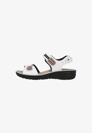 White open-toe sandal with black sole, adjustable straps, and brown patch details, designed for comfort and casual wear.