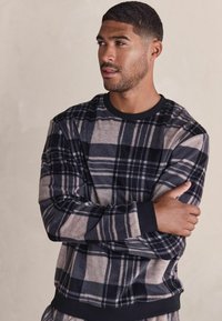 Fleece-Sweatshirt mit einem grau und dunkelblauen Karomuster sowie schwarzen Akzenten. Rundhalsausschnitt und gerippte Bündchen und Saum. Weiche Textur.