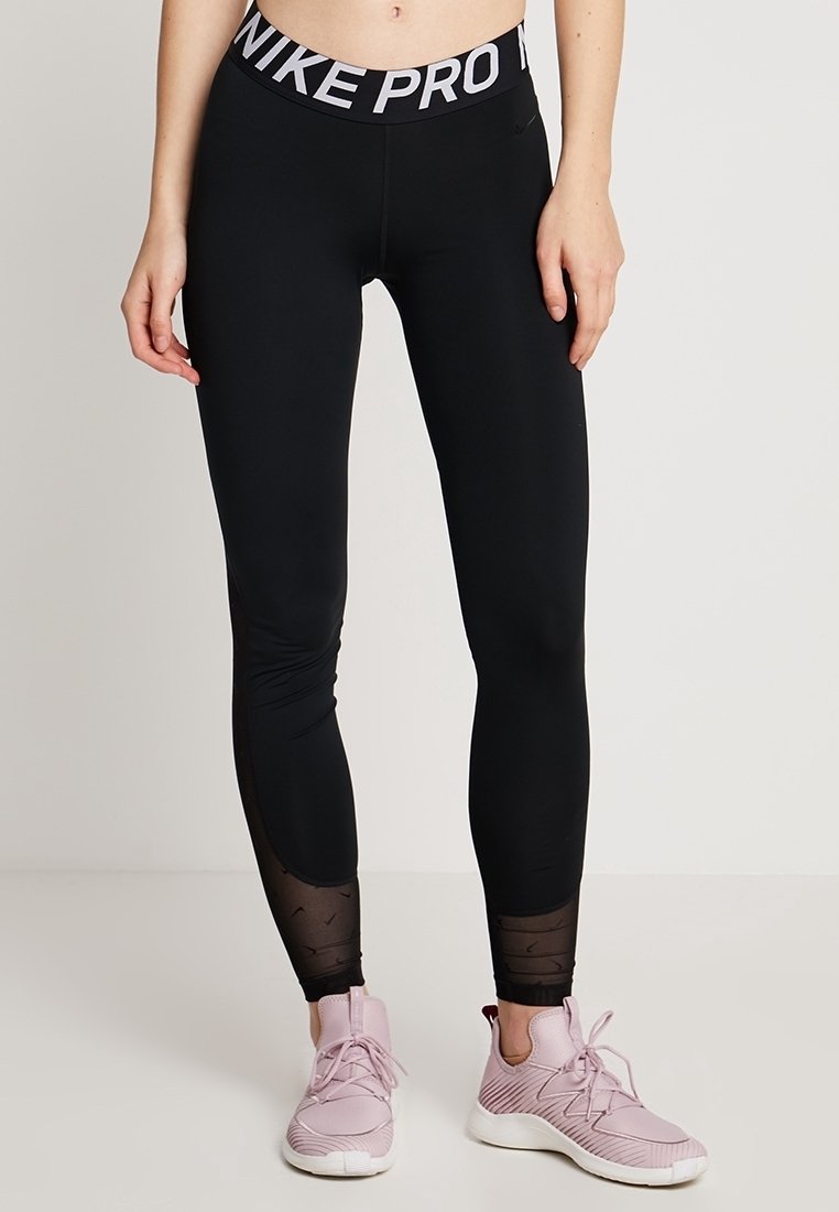 Svarta sport leggings med en bred midjeband där "NIKE PRO" är tryckt i vitt. Texturerade paneler vid vaden ger visuell intress. 