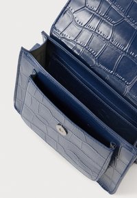 Tumesinine kunstnahast rahakott krokodilli tekstuuriga, millel on mitmed sektsioonid ja hõbedane snapsulgu.