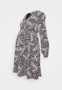Vestido de maternidade com padrão preto e branco, decote em V, mangas longas bufantes e cintura com cordão. Tecido fluido. Design de comprimento médio.