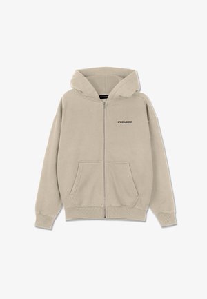 Beige zip-up hoodie van zacht materiaal, met een rits aan de voorkant, twee zijzakken en een zwart "PEGADOR"-logo op de borst.