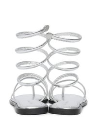 Silberne metallische Sandalen mit spiralförmigen Knöchelriemen und einer flachen schwarzen Sohle, die eine glatte Textur und ein minimalistisches Design aufweisen.