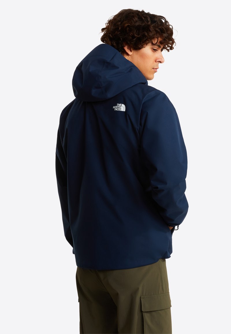 Veste imperméable marine avec capuche. Présente un logo au dos, une texture lisse et des manches longues avec des poignets ajustables.