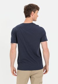 Granatowa koszulka z krótkim rękawem, okrągłym dekoltem, luźnym krojem i gładką teksturą; ma subtelny wzór melanżowy oraz płaskie szwy.