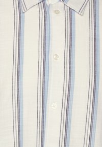 Camisa de manga corta con patrón de rayas verticales en azul y marino sobre un fondo blanco, con un cuello abotonado y botones transparentes.