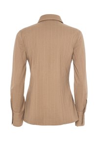 Blusa marrone a righe sottili con design aderente, maniche lunghe, colletto standard e silhouette sartoriale. Tessuto testurizzato, senza hardware visibile.