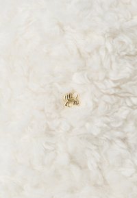 Χρυσό λογότυπο "SS" που αλληλοσυνδέεται, μαγνητισμένο σε απαλό, αφράτο λευκό μαλλί ή ύφασμα φλις.