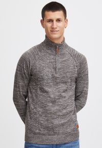 Grå flekkete zip-up genser med høy krage, ribbestrikkede mansjetter og kant, og en liten lærmerke detalj ved livet.