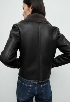 Zwart leren cropped jack met een zachte grijze bontkraag, met op maat gemaakte schouders en een soepele textuur, gedragen over blauwe jeans.