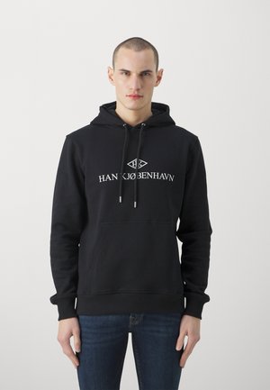 Zwarte hoodie met een kangoeroezak, trekkoordkap en het logo "HAN KØBENHAVN" in het wit. Kenmerkt zich door ribgebreide manchetten en zoom.
