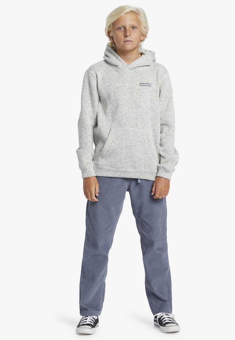 Grijze fleece hoodie met een voorzak, verstelbare trekkoordcapuchon, gedragen met blauwe corduroybroek en zwarte sneakers. Eenvoudig ontwerp, casual pasvorm.
