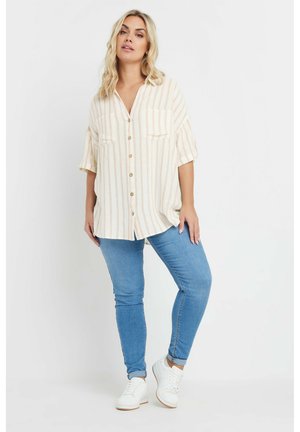 Camicia button-up a righe chiare con due tasche frontali, abbinata a jeans skinny blu e sneakers bianche. Progettata con una vestibilità comoda.