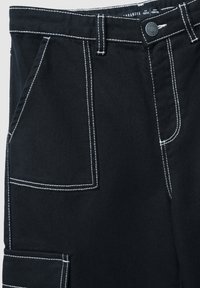 Czarne dżinsy z białymi kontrastującymi przeszyciami, wieloma kieszeniami, szlufkami na pasek i zapięciem na guzik w talii.