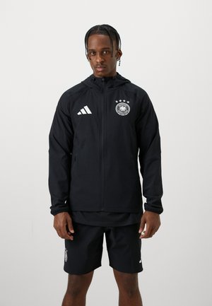 Schwarze wasserdichte Jacke mit durchgehendem Reißverschluss, Kapuze und weißem Adidas-Logo. Auf der Brust befindet sich das Emblem der deutschen Nationalmannschaft mit vier Sternen.