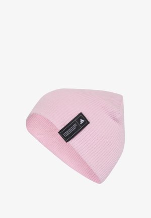 Pink knitted beanie with a ribbed texture, featuring a black label with white text on one side. The hat has a tapered crown and straight edge.