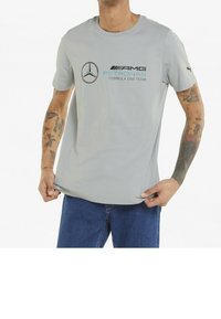 Gray t-shirt made of soft fabric featuring the Mercedes logo and "AMG PETRONAS Formula One Team" printed in black and teal.