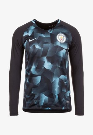 Maillot de sport noir à manches longues avec motif géométrique bleu, logo Nike sur la poitrine gauche, et écusson du club de football Manchester City sur la poitrine droite.
