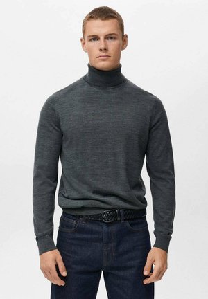 Suéter de cuello alto gris oscuro hecho de un tejido suave, con mangas largas y un diseño ajustado, combinado con jeans oscuros y un cinturón trenzado.