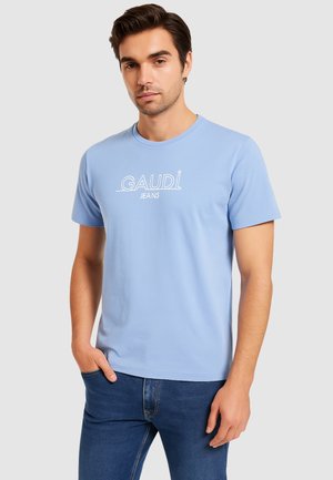 T-shirt di cotone azzurro chiaro con maniche corte e colletto a girocollo, con la scritta "GAUDI JEANS" stampata in bianco sulla parte anteriore. Inclusi jeans in denim.