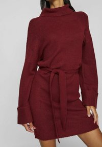 Robe en maille bourgogne avec col montant, manches longues et ceinture nouée. Comprend des poignets et un ourlet côtelés, une texture douce et une coupe décontractée.
