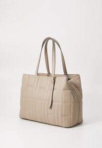 Sac tote matelassé beige en cuir lisse, avec des bretelles doubles et une fermeture éclair unique. Reconnaissable par sa forme rectangulaire et sa texture subtile.