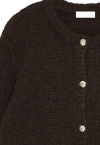 Brūns teksturēts kardigāns ar apaļu rakstainu kaklu un zelta spirāles pogām. Mīksta, pūkaina auduma un vienkāršs, klasiskas dizains.