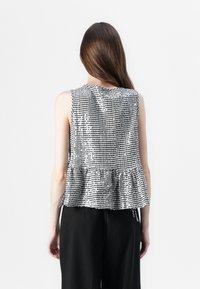 Zwart-wit geruit mouwloos topje met een peplumzoom, gemaakt van gestructureerde stof. De achterkant heeft een ronde halslijn en zichtbare naden.