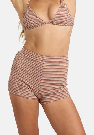 Femme portant une tenue assortie en maille côtelée deux pièces avec des rayures horizontales multicolores, comprenant un haut de bikini et un short taille haute.