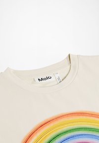 Beżowa bawełniana koszulka z multi-kolorowym haftowanym wzorem tęczy na przodzie, z okrągłym dekoltem i widoczną metką wewnątrz.