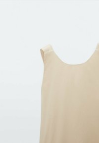 Beżowa sukienka bez rękawów z szerokimi ramiączkami i okrągłym dekoltem na jednolitym jasnym tle.