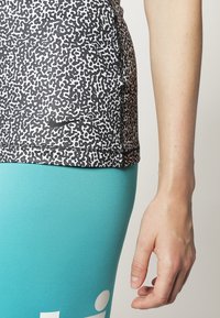 Top sportivo a righe in bianco e nero con silhouette aderente, abbinato a leggings blu con dettagli del logo in bianco.