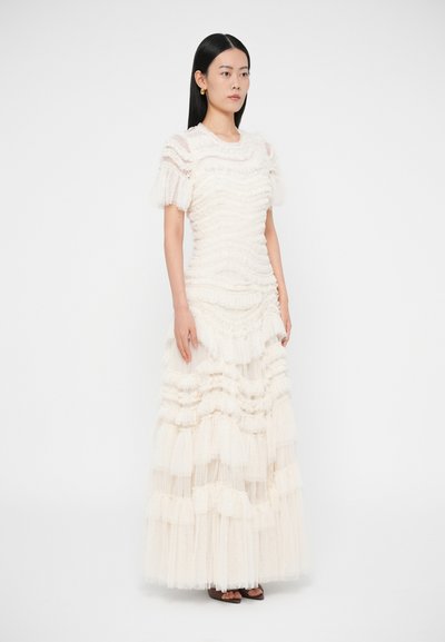 Rochie albă în straturi dintr-un material texturat, cu mâneci scurte cu volane și o siluetă până la gleznă cu straturi în cascadă.