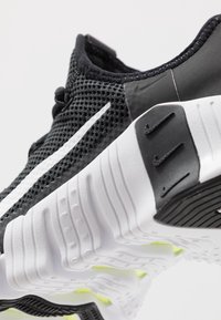 Sort og hvid atletiksko med åndbart mesh-øvre, karakteristisk sålmønster og hvid swoosh-logo på siden.