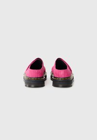 Fuchsia suede slip-on shoes with black rubber soles and yellow stitching along the edge, featuring rounded toes and minimal design details.