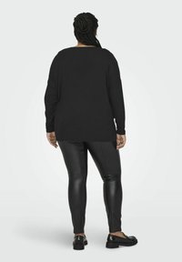 Černý top s dlouhým rukávem a širokým výstřihem, spárovaný s černými legínami z umělé kůže a černými slip-on botami s tlustou podrážkou.