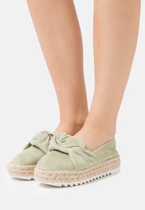 Alpargatas de gamuza verde con detalle de lazo anudado, suela envuelta en yute y suela exterior de goma blanca texturizada.